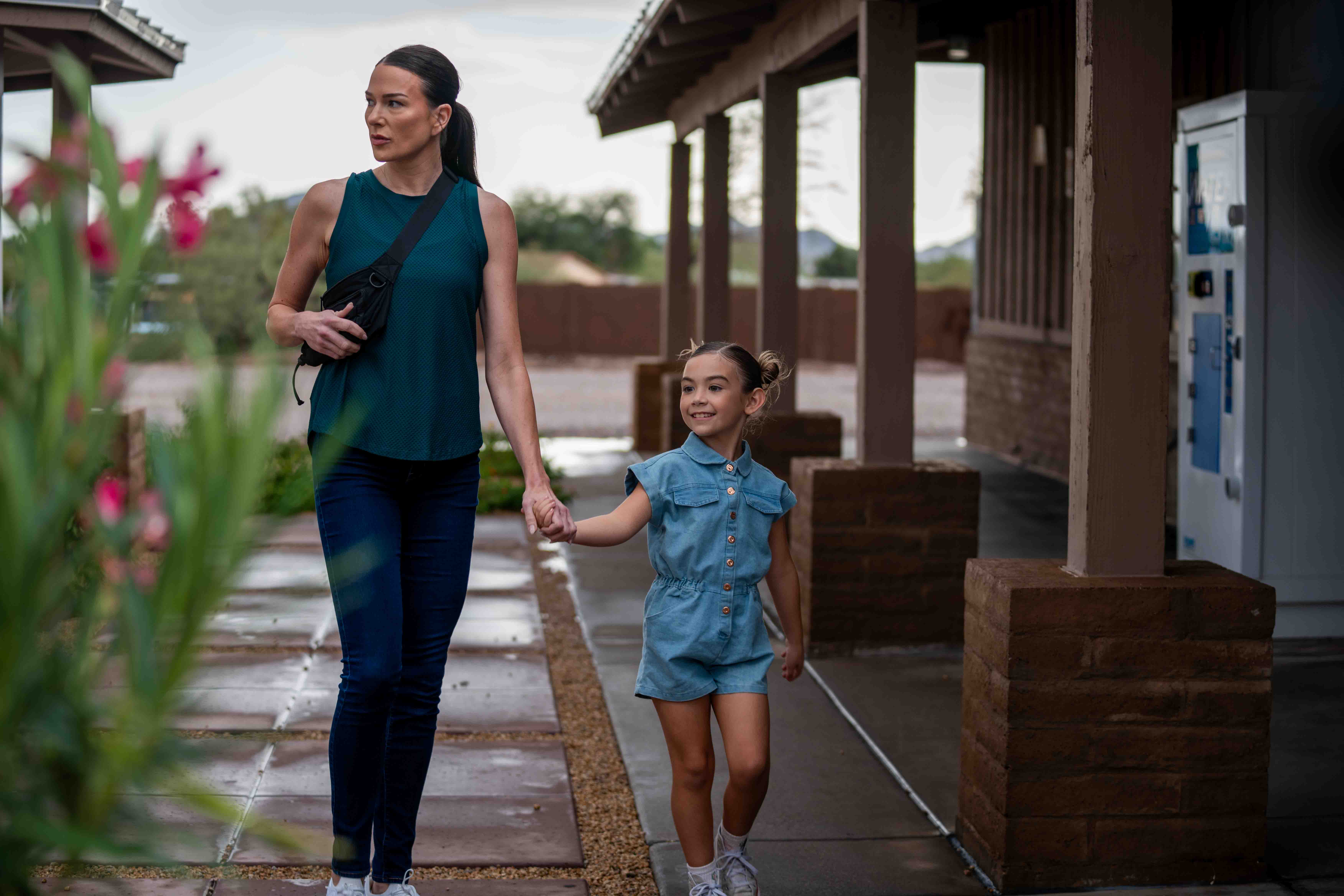 A mother and daughter walking hand in hand along a path